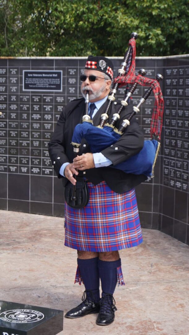 A man in a kilt is carrying a bagpipe.