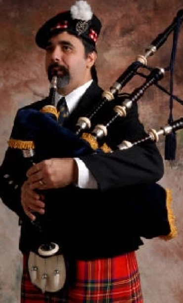 A man in a suit playing the bagpipes.