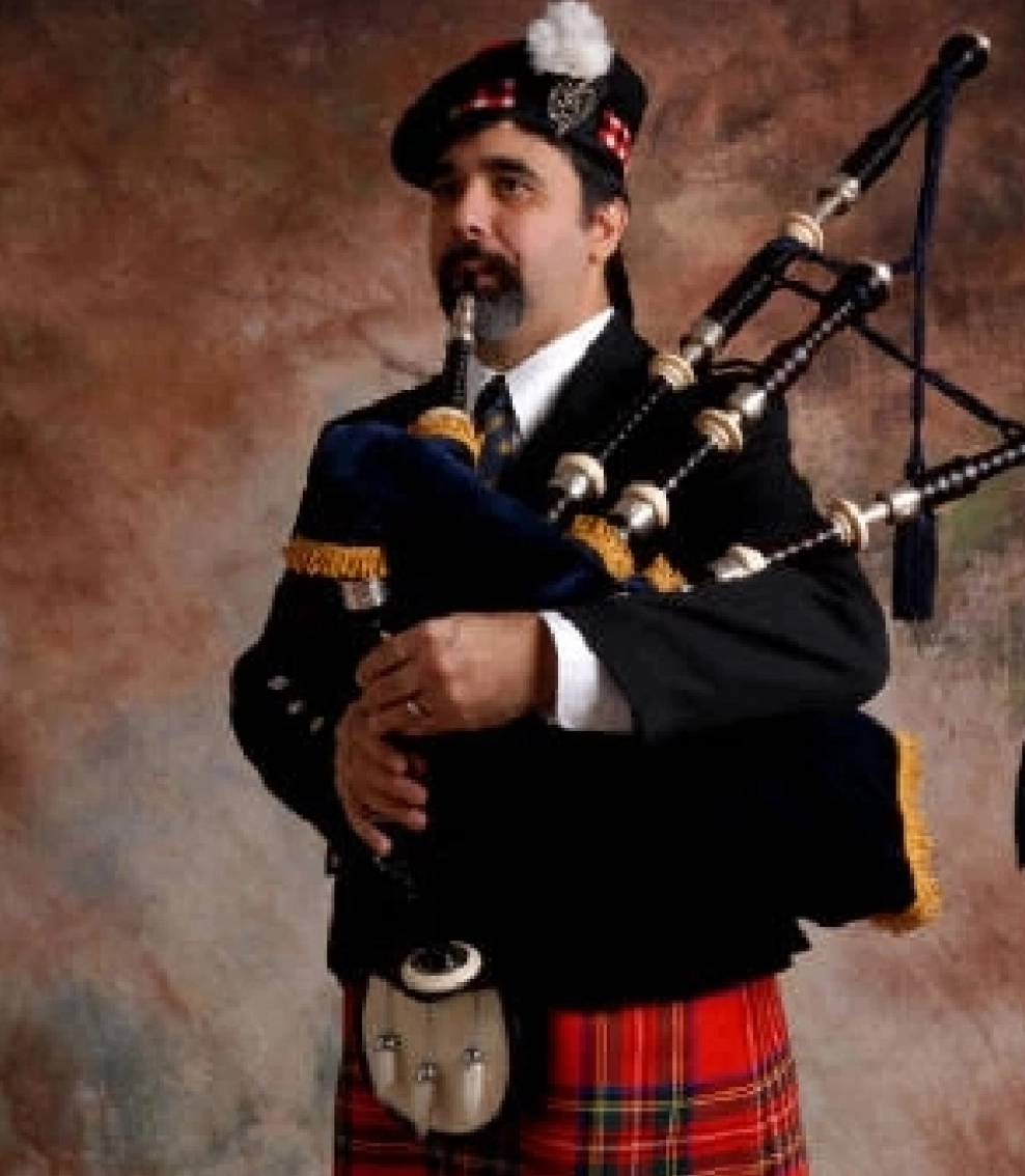 A man in a kilt playing the bagpipes.