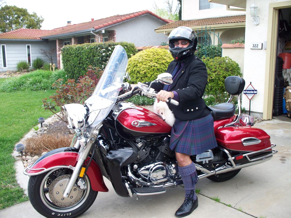 A man in kilt on motorcycle with helmet.